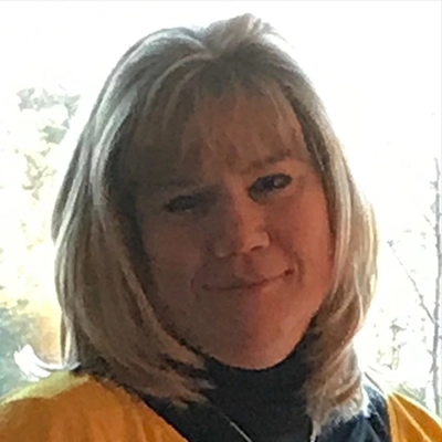 Headshot of Heather Woo, photographed indoors with natural light from a window in the background.