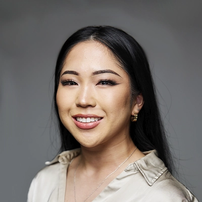 Headshot of Dr. Jenna Taira wearing a light-colored blouse against a gray studio background.